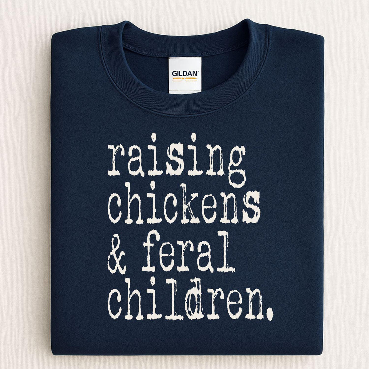 Folded navy sweatshirt reading Raising Chickens and Feral Children