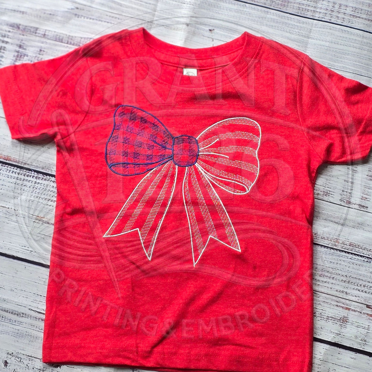 Red kids embroidered red, white, and blue gingham bow shirt flat lay