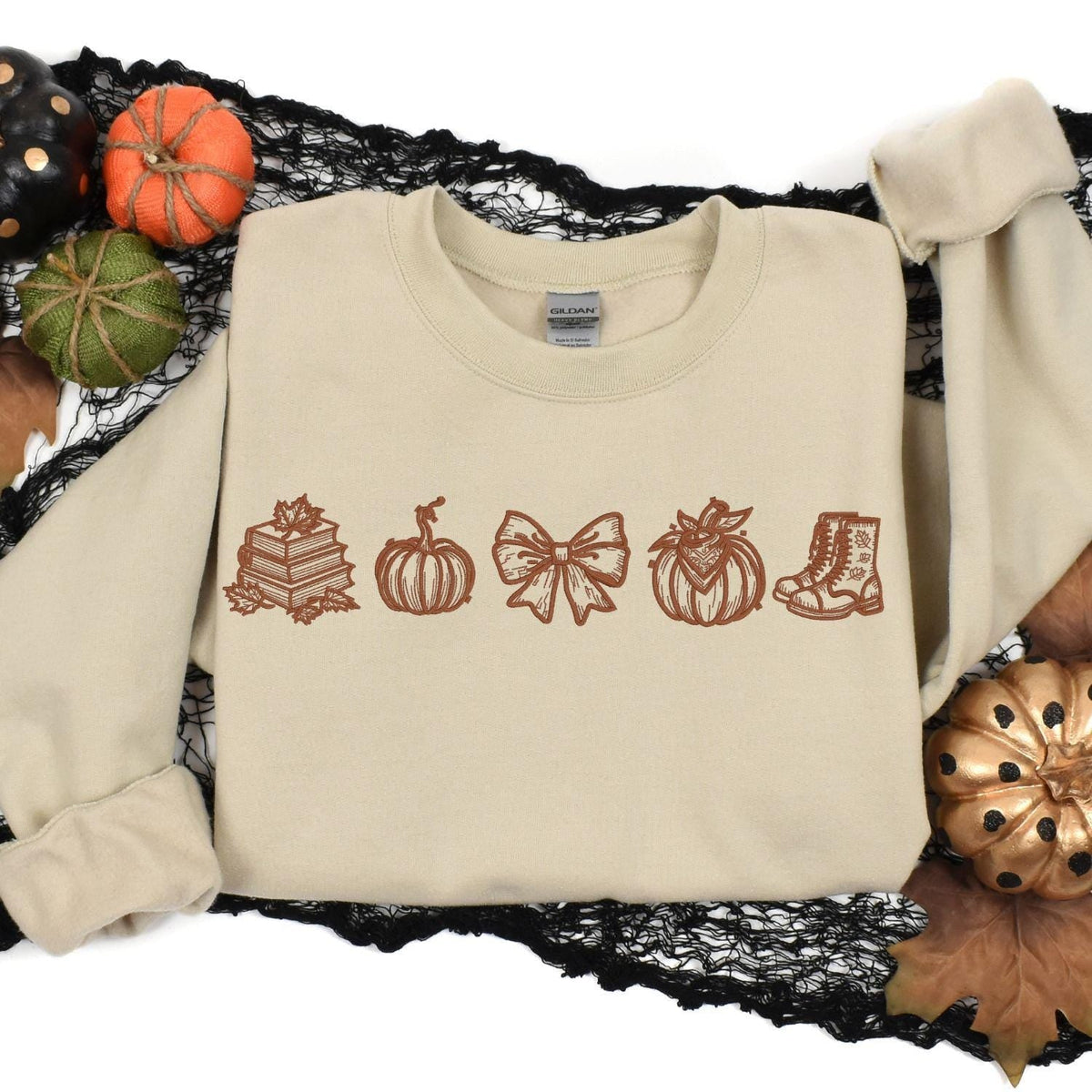 Sand embroidered autumn books and pumpkins crewneck styled with Halloween decor