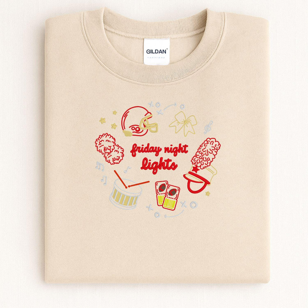 Sand Gildan crewneck with embroidered football helmet, pom-poms, megaphone and drum