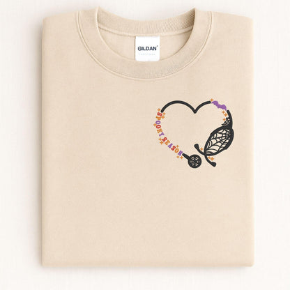 Folded Sand nurse sweatshirt with embroidered stethoscope heart and bats