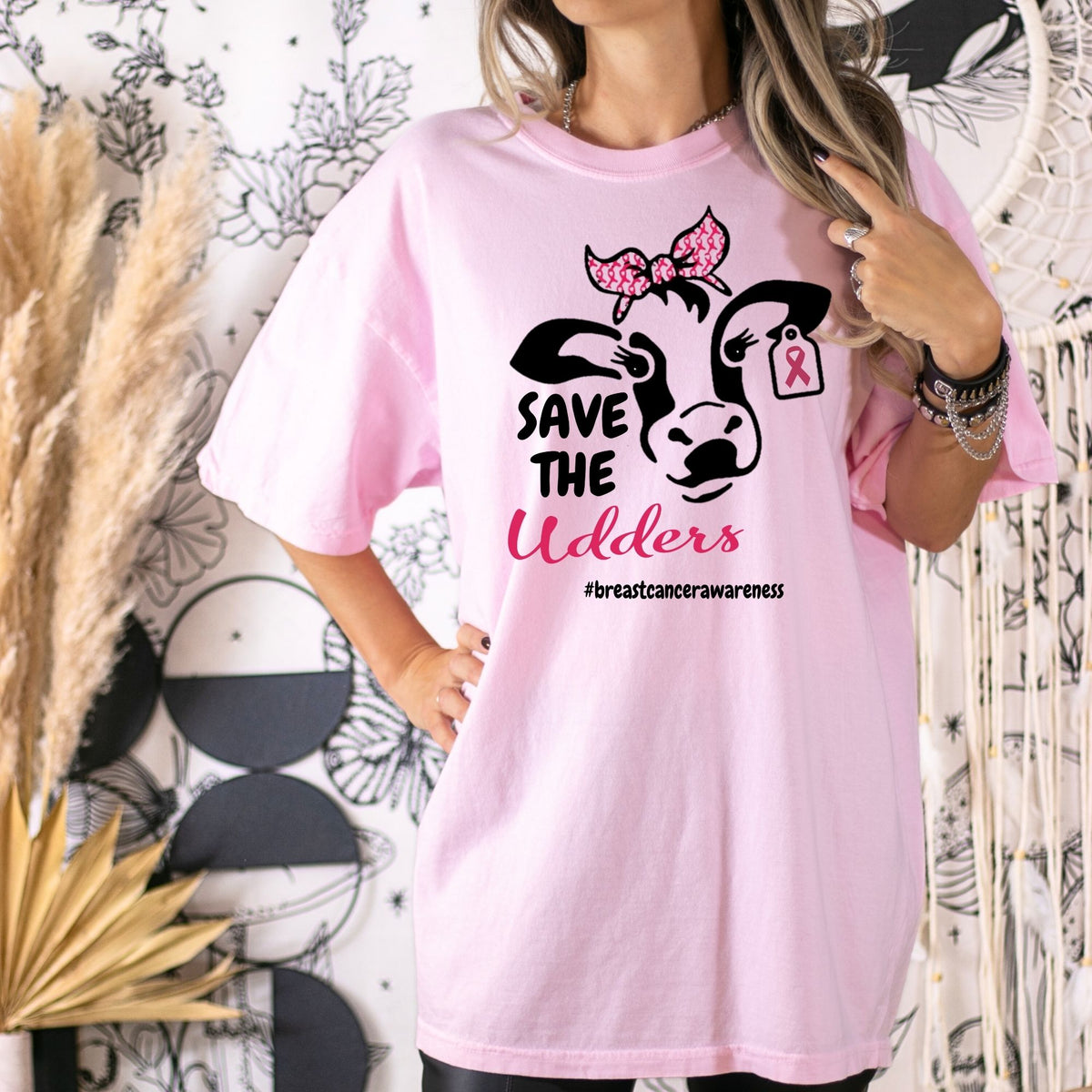 Pink Save the Udders cow graphic shirt modeled with one hand on the hip