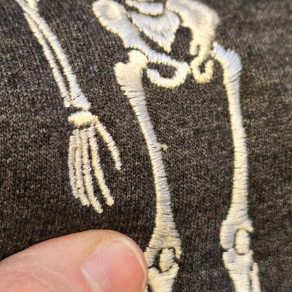 Close-up of white skeleton embroidery stitching on a Heather Black Gildan Softstyle sweatshirt