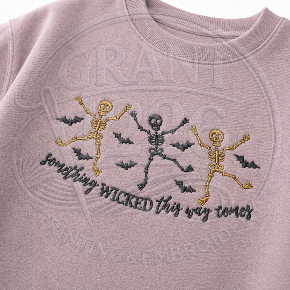 Close-up of dancing skeleton Halloween embroidery with bats and Something Wicked This Way Comes stitched lettering