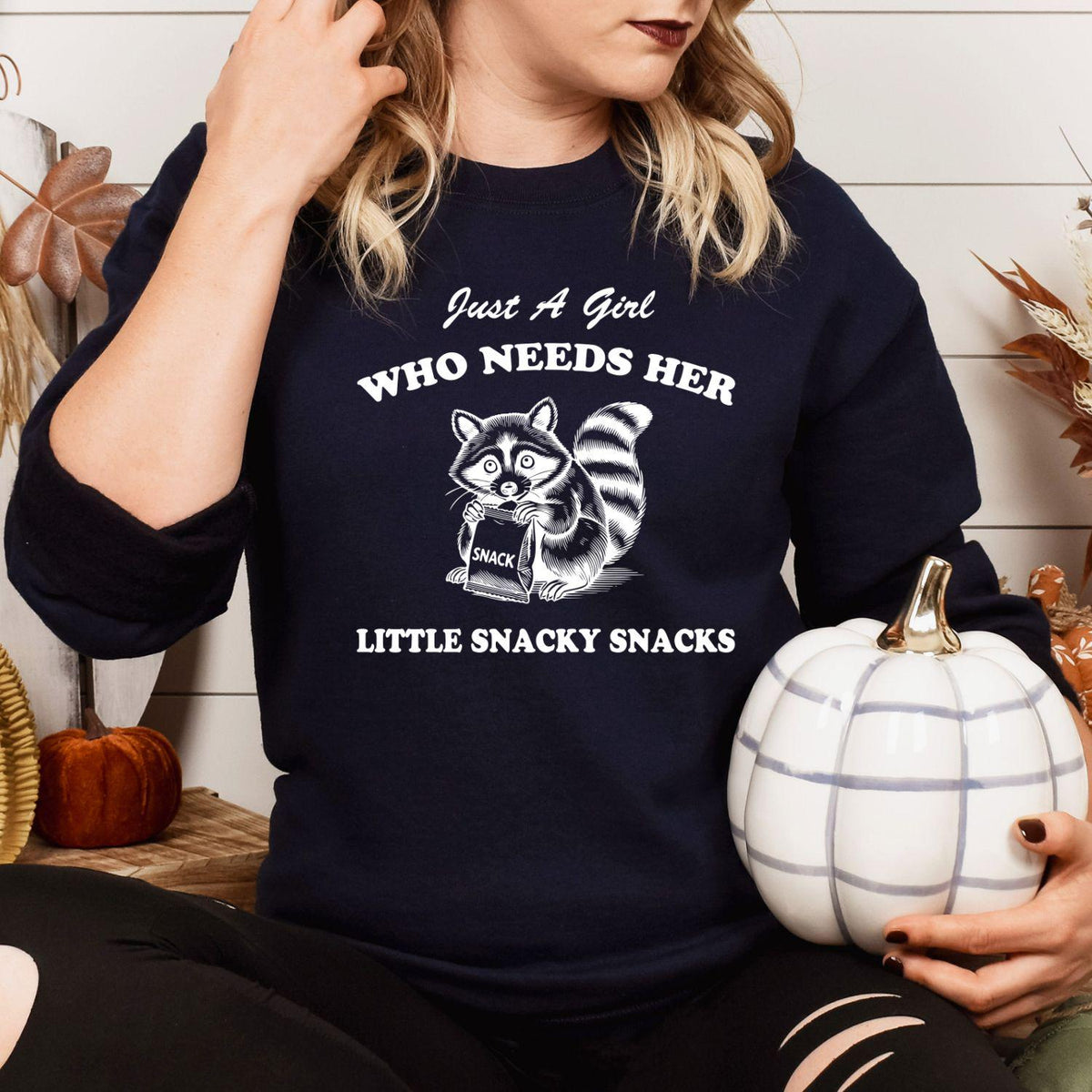 Navy funny snacky raccoon sweatshirt modeled while holding a white pumpkin
