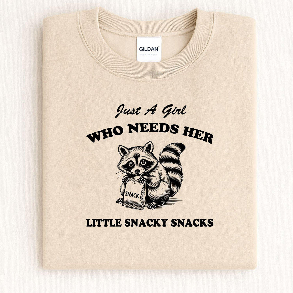 Sand Just a Girl snacky raccoon crewneck folded for a front view