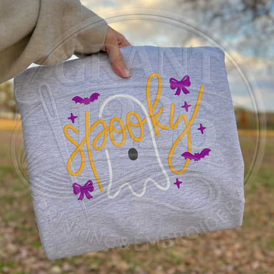 Folded Ash Gildan Softstyle sweatshirt showing gold Spooky script embroidered over a white ghost with purple bats and bows
