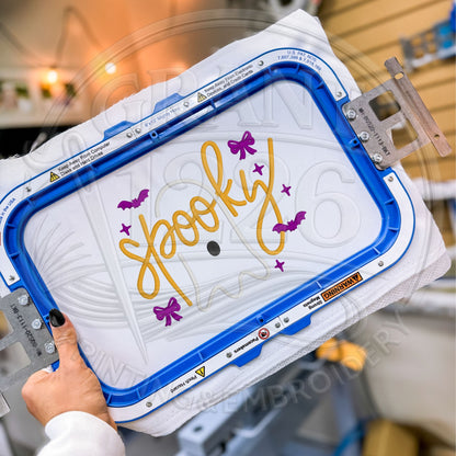 Spooky ghost sweatshirt embroidery design shown in a commercial embroidery hoop during production