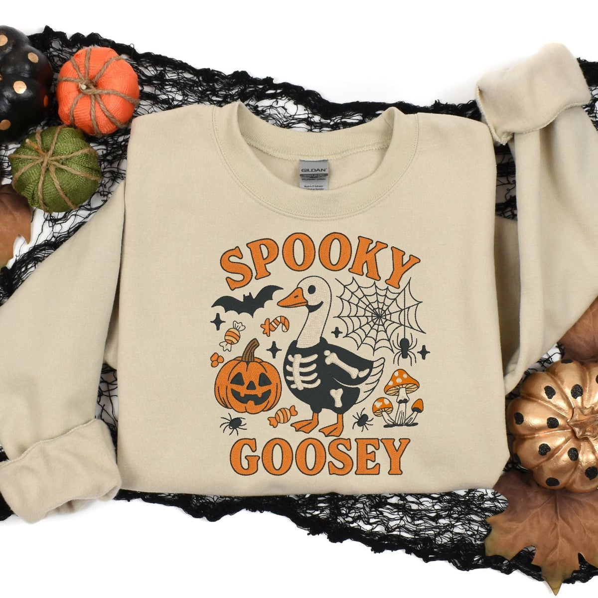 Sand Spooky Goosey sweatshirt flat lay with Halloween pumpkins and black lace