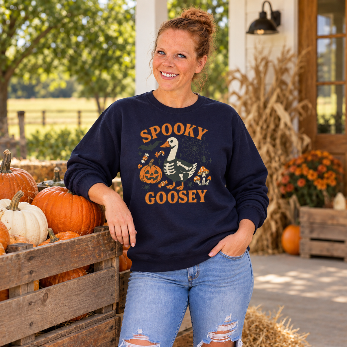 Woman wearing Navy Spooky Goosey embroidered sweatshirt beside pumpkins