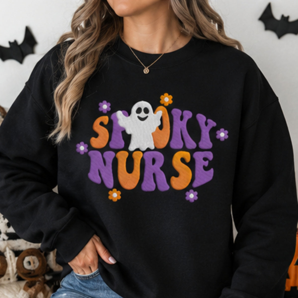 Woman wearing black Spooky Nurse embroidered Halloween sweatshirt with purple orange and white ghost design