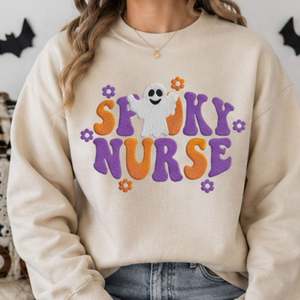 Woman wearing sand Spooky Nurse Halloween crewneck with embroidered ghost and purple orange lettering