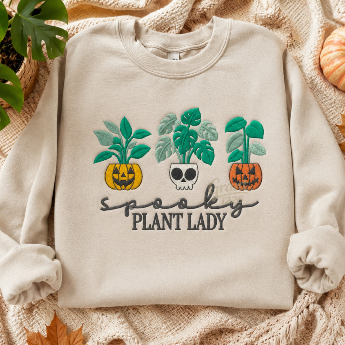 Sand embroidered Spooky Plant Lady Gildan crewneck sweatshirt shown in a fall flat lay.