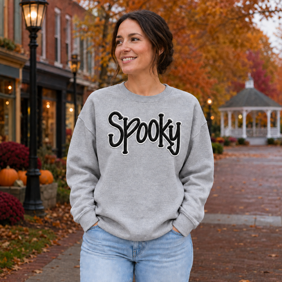 Adult woman wearing a sport gray Spooky puff embroidery sweatshirt with black and white thread