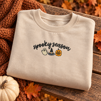 Folded sand sweatshirt featuring the 8 by 3 inch Spooky Season embroidery