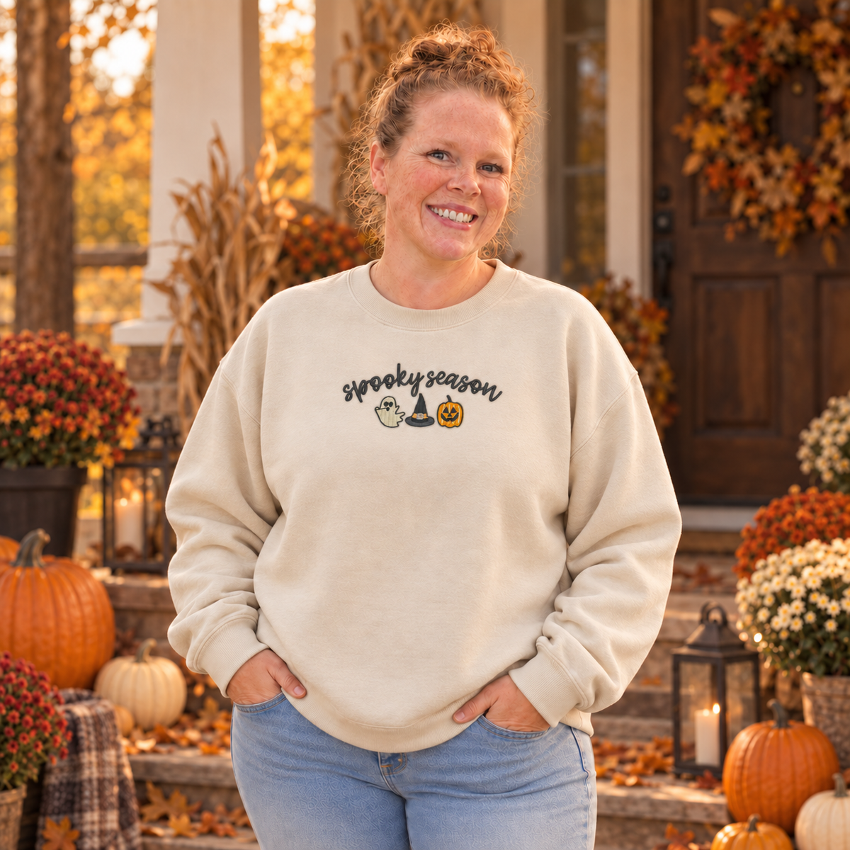 Woman wearing a sand sweatshirt with an 8 by 3 inch Spooky Season embroidered chest design