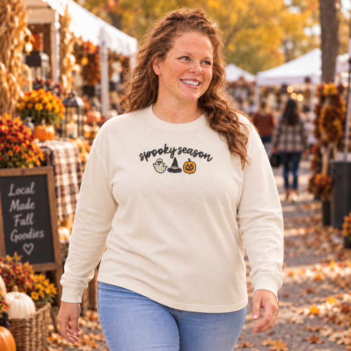 Woman wearing an ivory Spooky Season embroidered long sleeve shirt at an autumn market