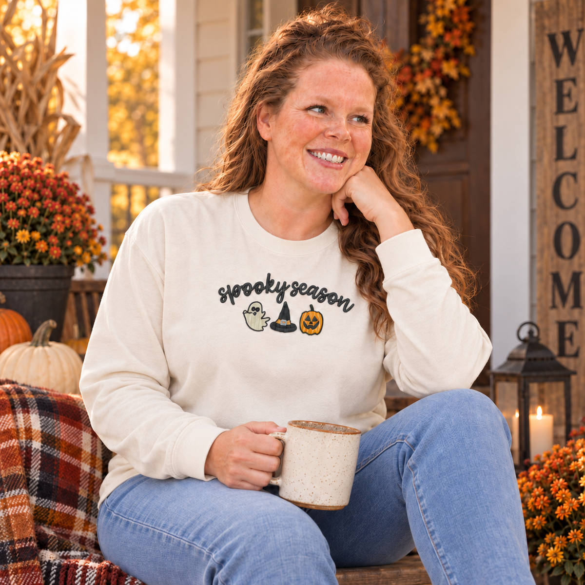 Woman seated on a fall porch wearing an ivory Spooky Season embroidered long sleeve shirt