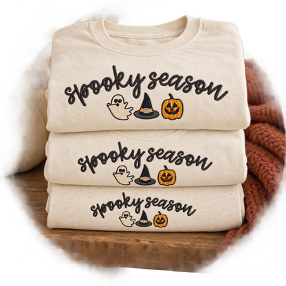 Folded adult youth and toddler ivory shirts with matching Spooky Season embroidery
