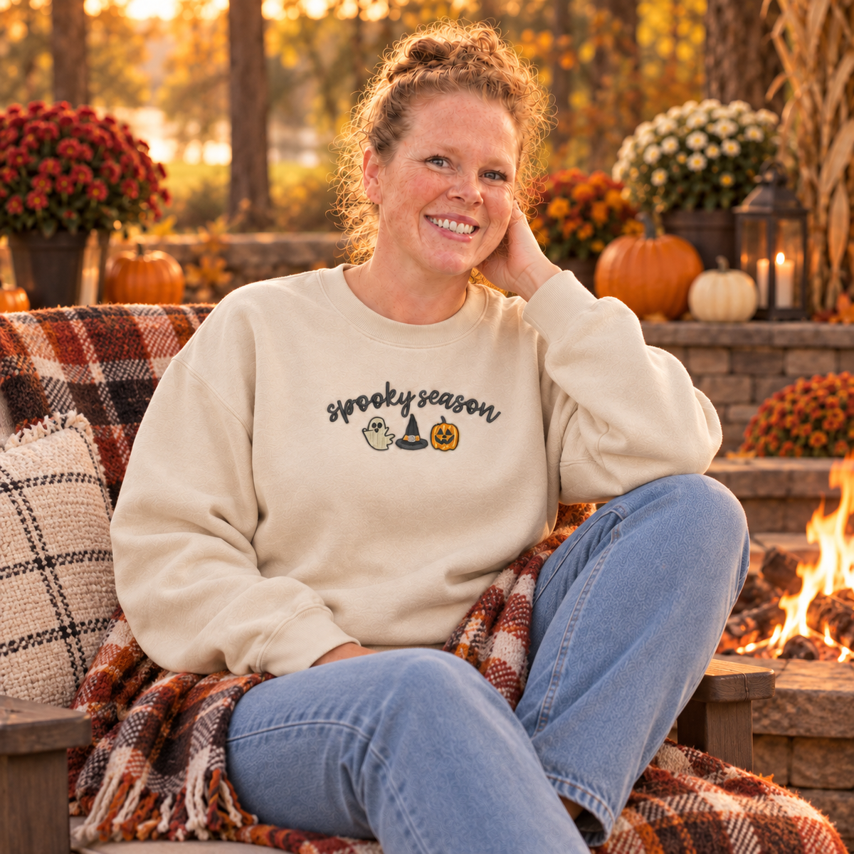 Sand Spooky Season embroidered sweatshirt worn beside a fall firepit