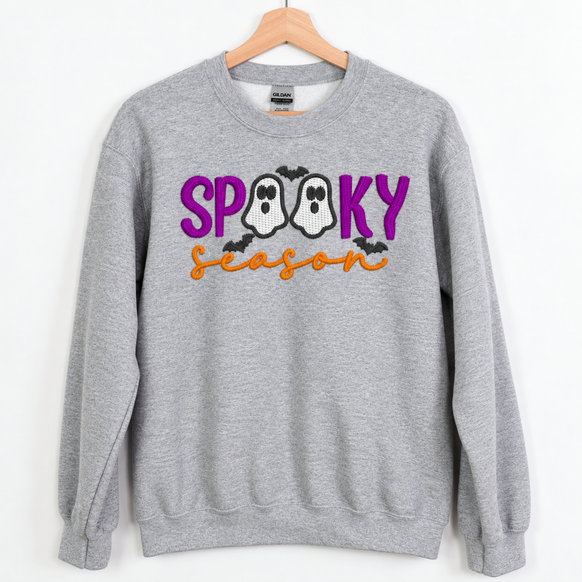 Spooky Season ghost embroidered Sport Grey sweatshirt on a wooden hanger, front view