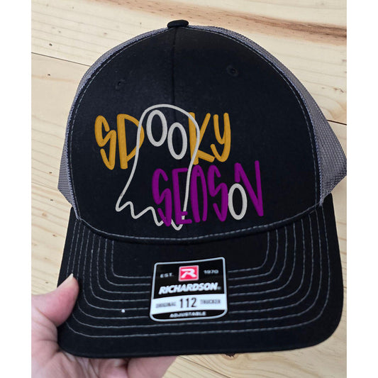 Black and charcoal Richardson 112 trucker hat with gold, purple and white Spooky Season ghost embroidery