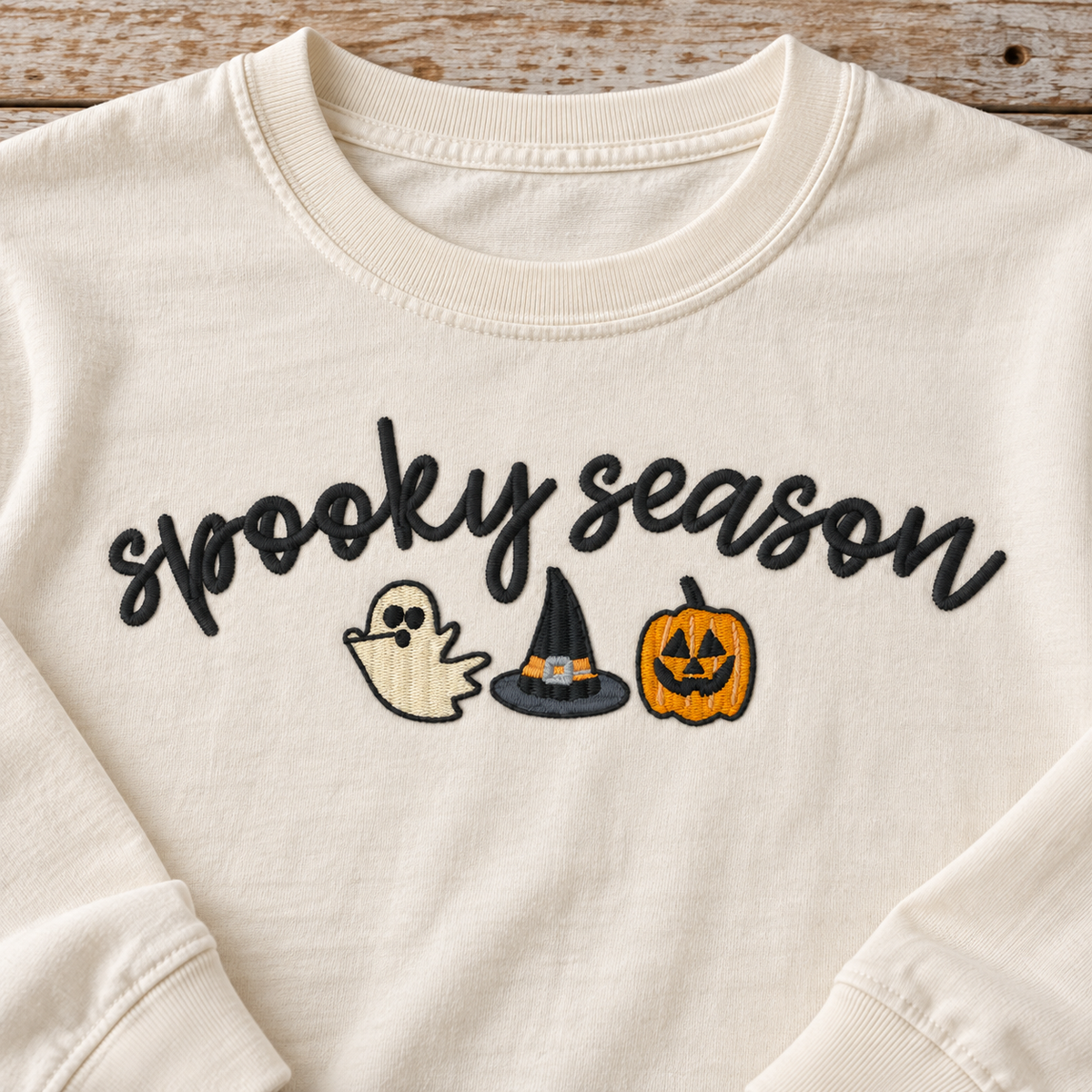 Close-up of Spooky Season embroidery on an ivory long sleeve tee