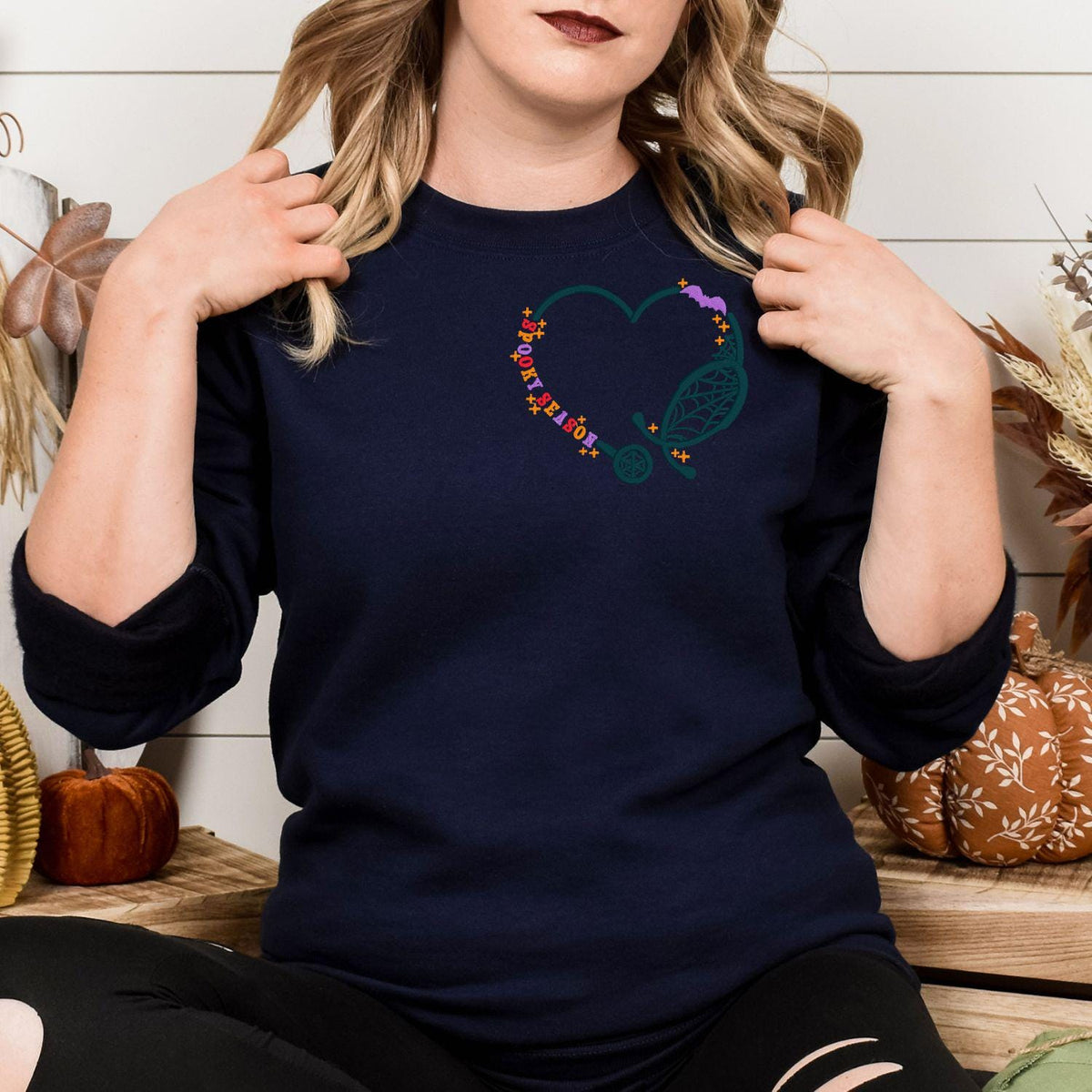 Navy Spooky Season nurse embroidered sweatshirt with stethoscope heart, lifestyle view