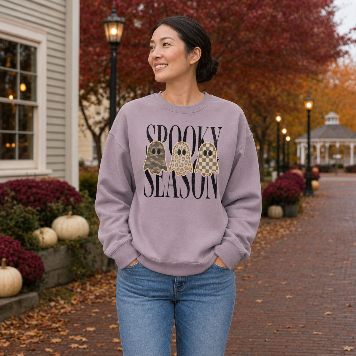 Woman wearing a Paragon Gildan Softstyle Spooky Season patchwork ghost sweatshirt in an autumn town