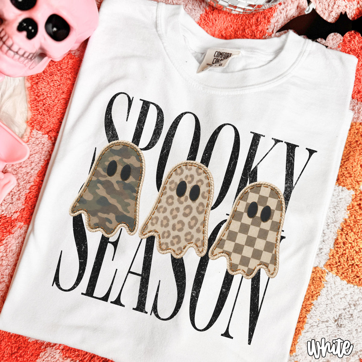Close-up of the camo leopard and checkered ghost graphic on a white Spooky Season shirt