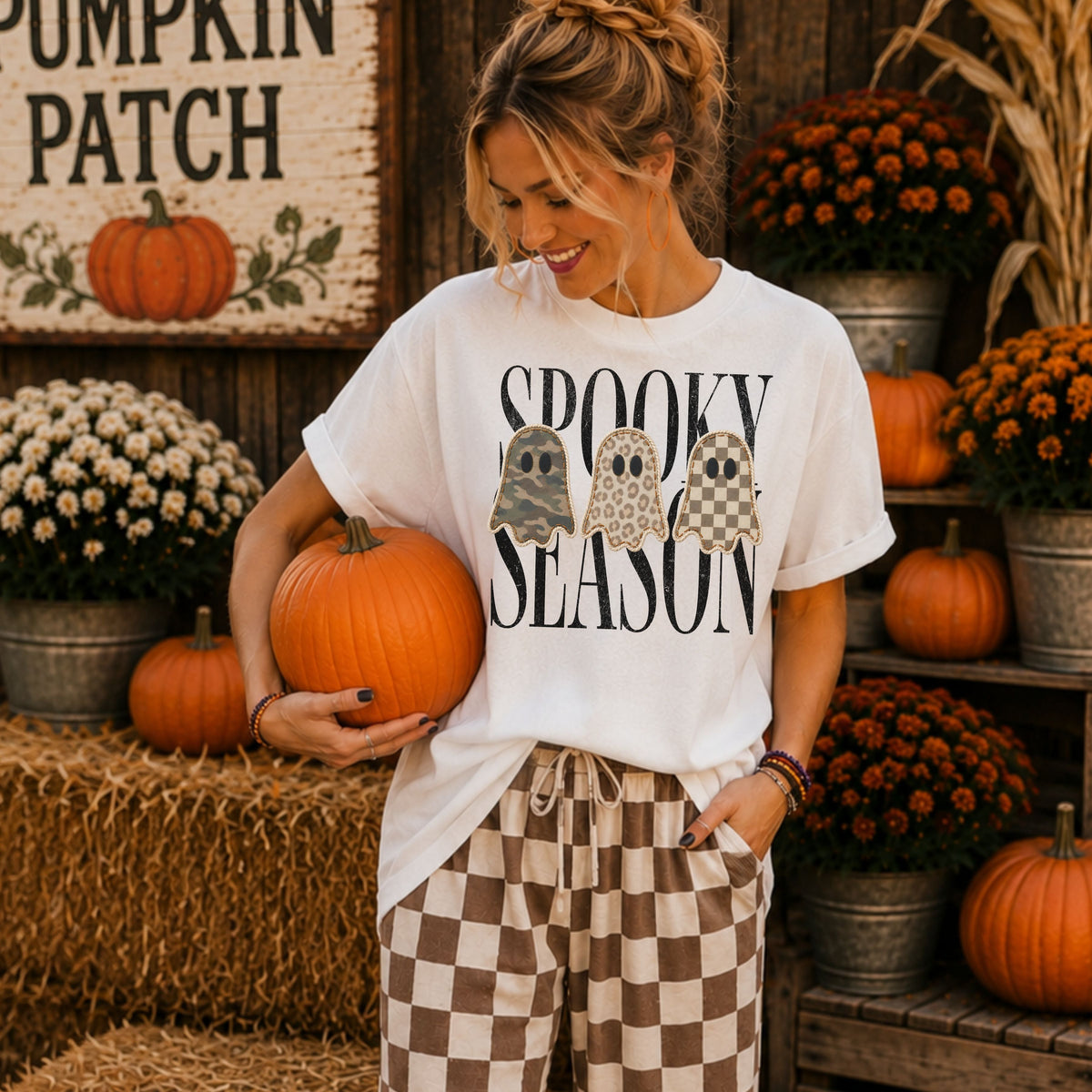 Woman wearing a white Spooky Season patchwork ghost DTG T-shirt at a fall pumpkin patch