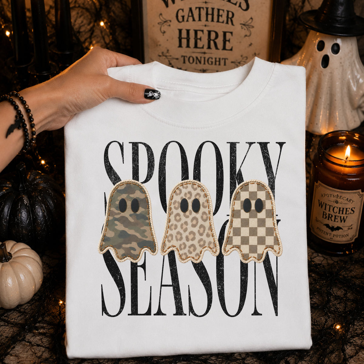 White Spooky Season patchwork ghost DTG shirt displayed with witchy Halloween decor