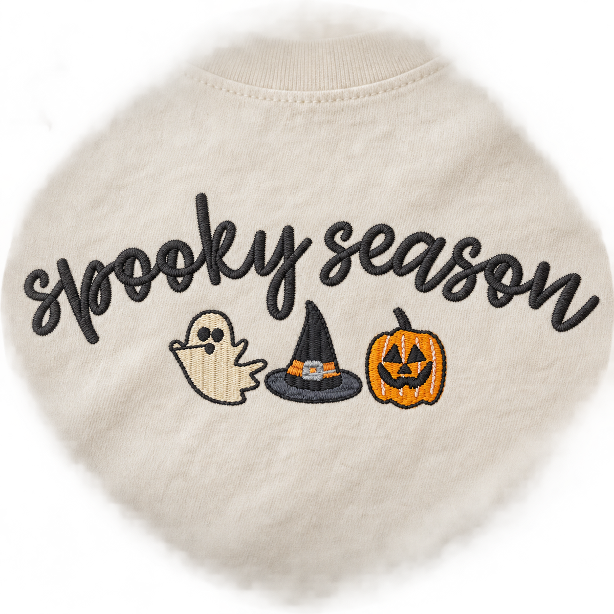 Close-up of black orange and cream Spooky Season machine embroidery on an ivory tee