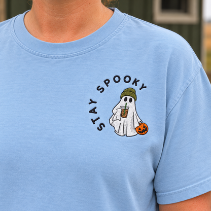 Close-up of raised Stay Spooky ghost embroidery with olive beanie, iced coffee and orange pumpkin bucket
