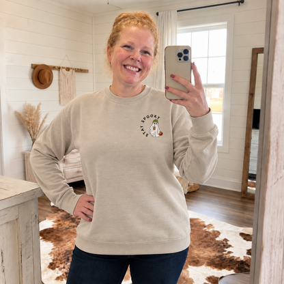 Woman wearing a Sand Gildan Softstyle sweatshirt with embroidered coffee ghost and pumpkin on the left chest