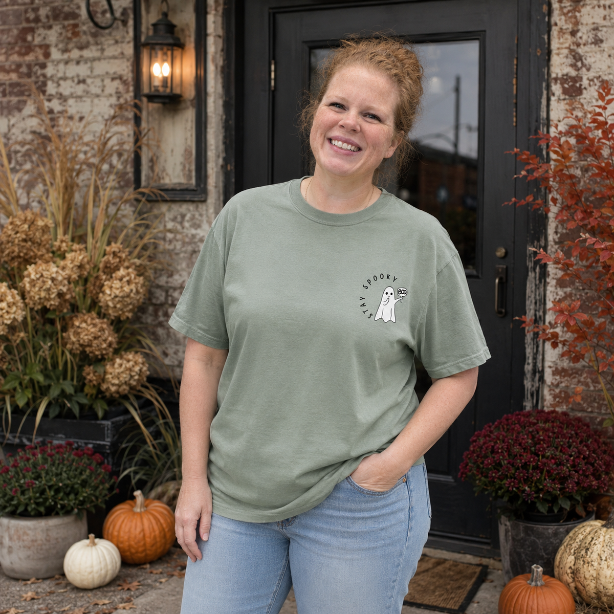 Stay Spooky ghost embroidered Comfort Colors 1717 Sage T-shirt modeled by Samantha in a fall storefront scene