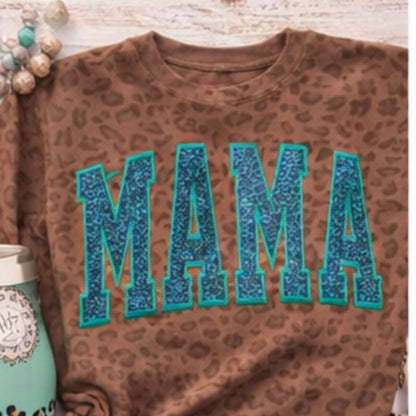 Brown leopard print shirt with blue 'MAMA' text on a wooden surface.