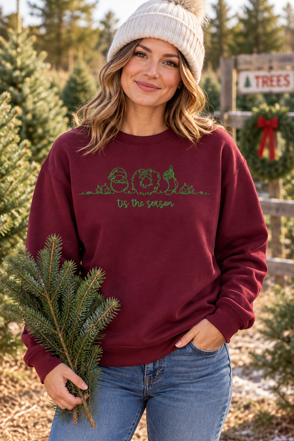 Woman wearing Maroon Tis The Season embroidered Christmas crewneck at tree farm