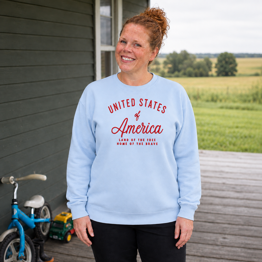 Samantha wearing a Hydrangea Comfort Colors sweatshirt embroidered with United States of America, Land of the Free, Home of the Brave