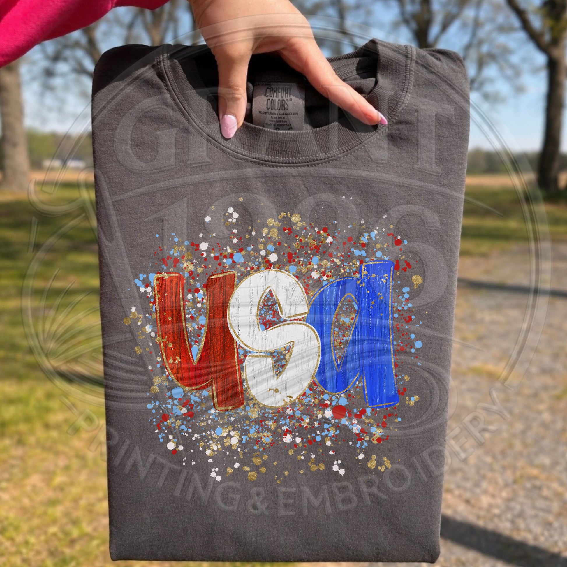 Dark gray patriotic USA graphic tee folded outdoors with red white and blue design