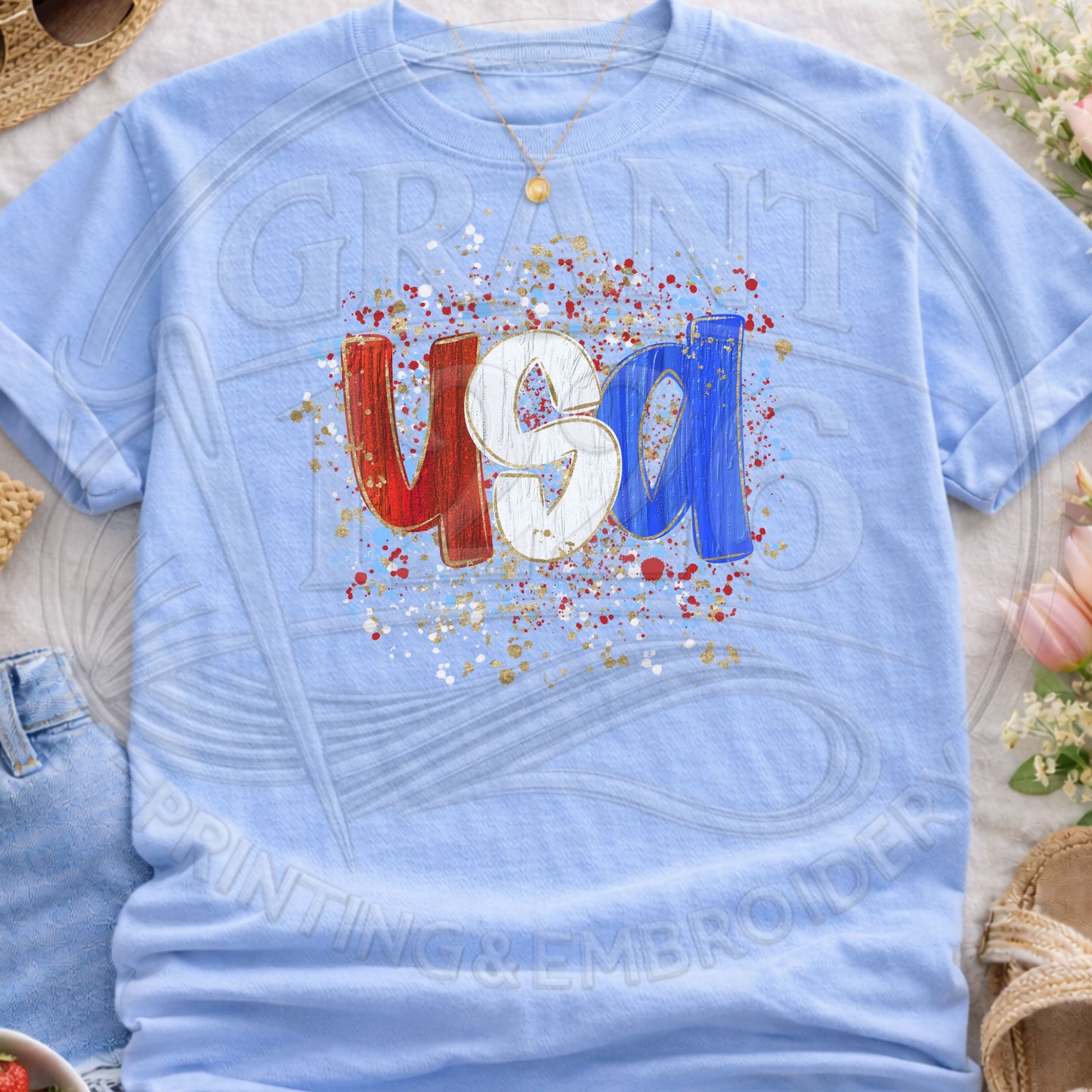 Light blue USA patriotic graphic t-shirt flatlay with trendy splatter design