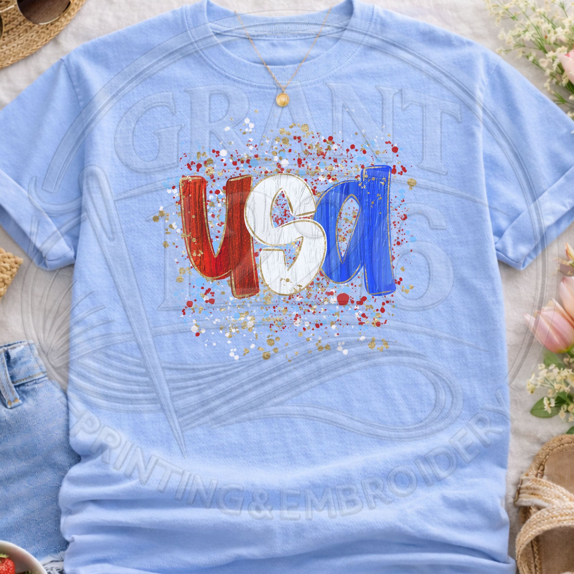 Light blue USA patriotic graphic t-shirt flatlay with trendy splatter design