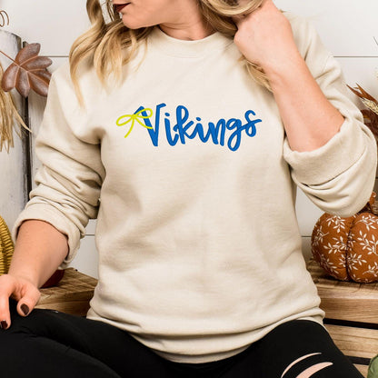 Sand Vikings script embroidered crewneck modeled indoors