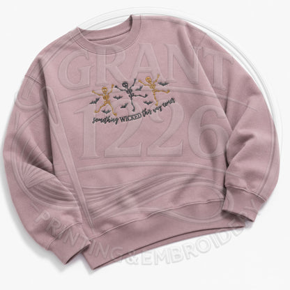 Mauve embroidered skeleton crewneck with Something Wicked This Way Comes text and dancing Halloween skeletons