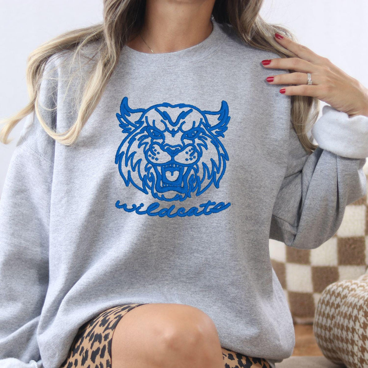 Sport gray sweatshirt with blue vintage Wildcats mascot embroidery modeled indoors