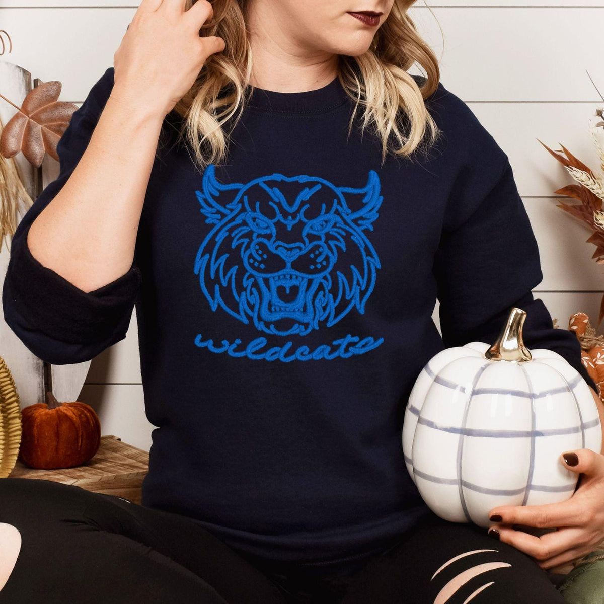 Navy Wildcats mascot sweatshirt modeled while holding a white pumpkin