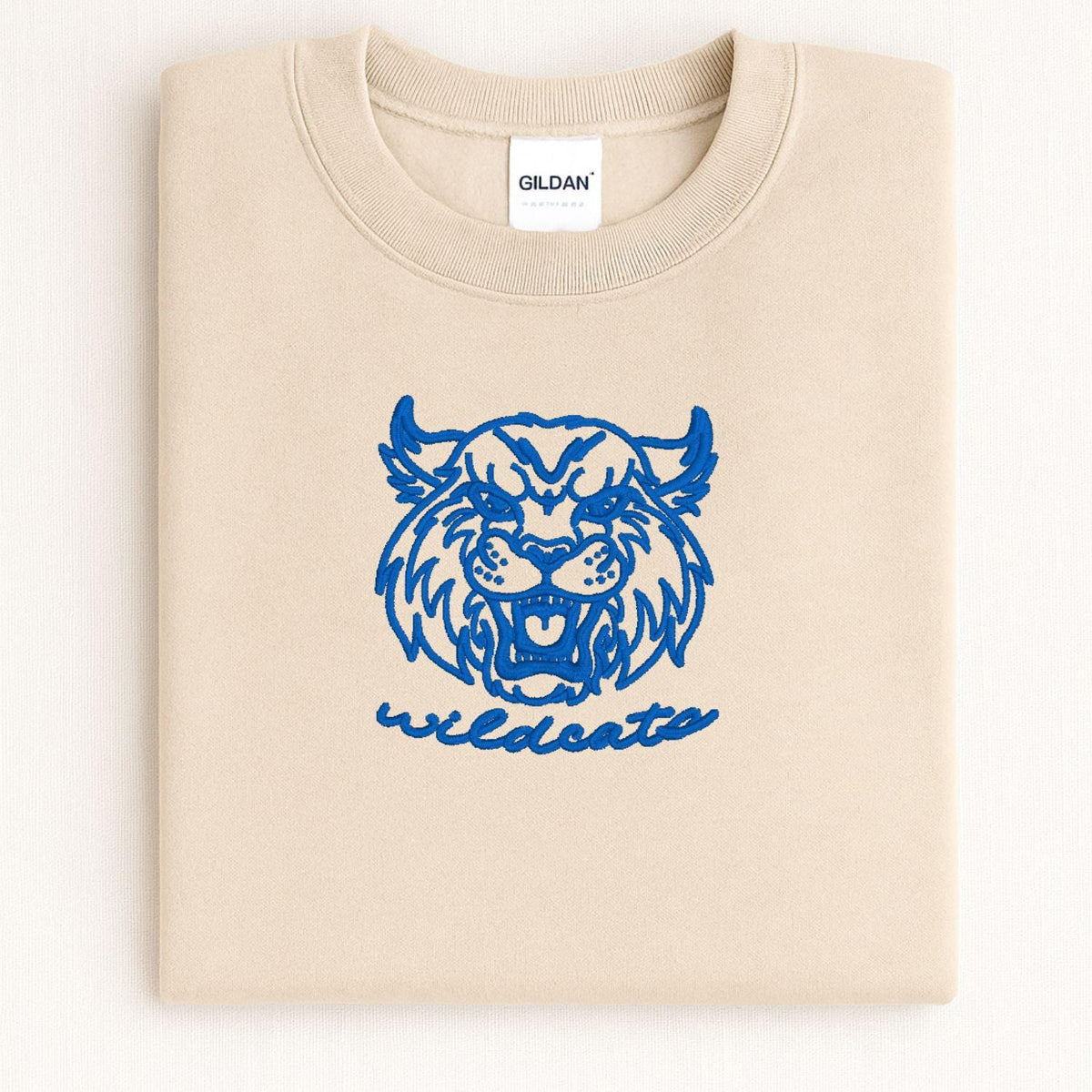 Sand Wildcats mascot embroidered crewneck folded on a light background
