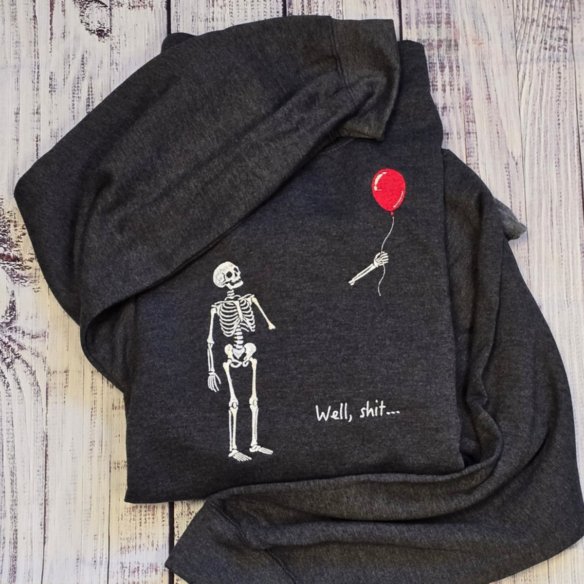 Heather Black Gildan Softstyle embroidered sweatshirt with skeleton, floating red balloon, and Well, shit phrase