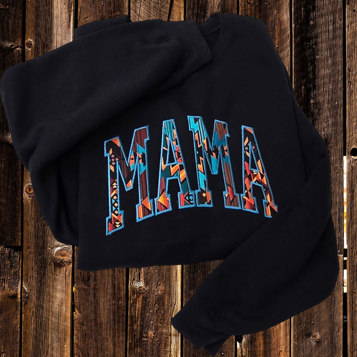Black Western mom sweatshirt with multicolor geometric MAMA embroidery on dark wood
