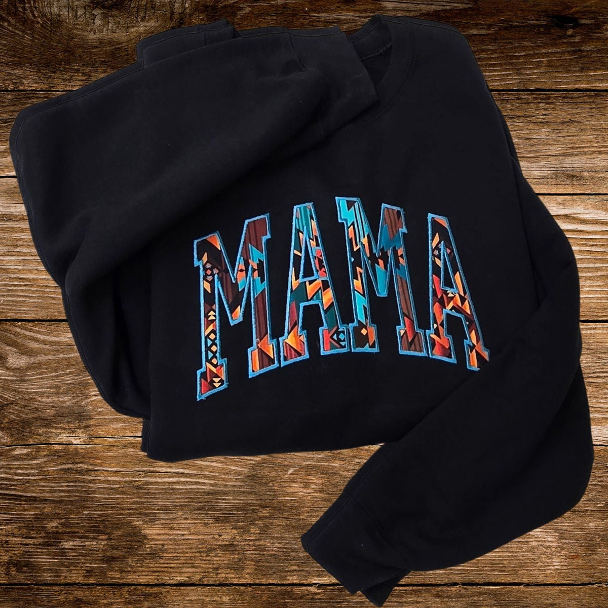 Black Western Mama embroidered sweatshirt displayed on a rustic wood background